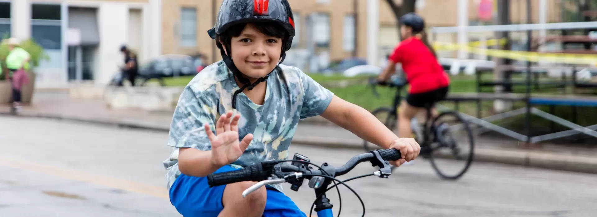 Boy on bike waiving at Siclovia